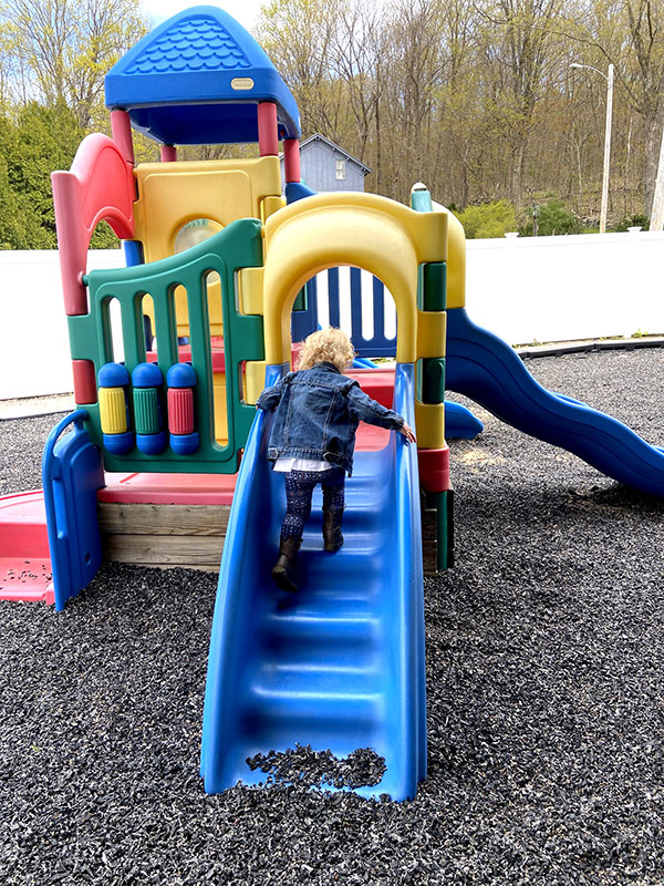 Young child climbing up stairs on an outdoor plastic playhouse.