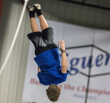 A kid flipping upside down in the air after bounding from a trampoline.