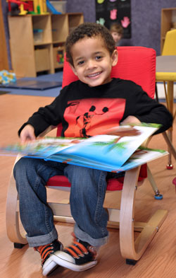 A child in the Gigueres Discovery School pre-k class reading a picture book.