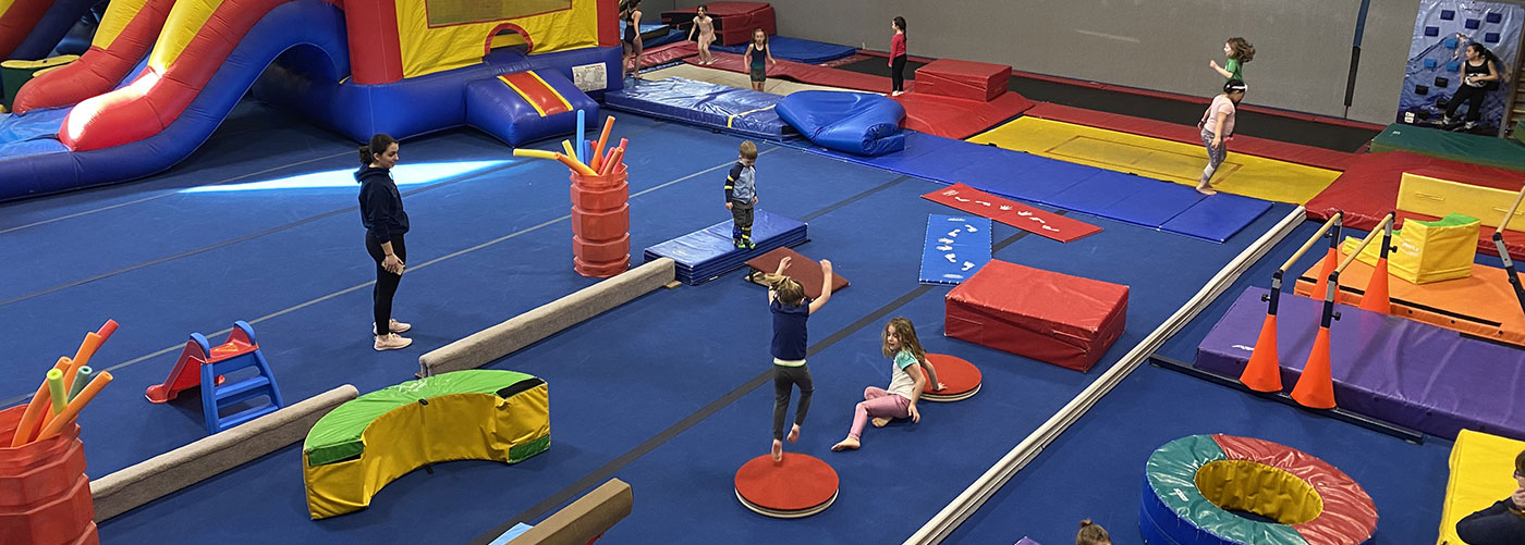 Overview of Gigueres gym during a kids party event, including soft gym equipment and bouncy castle.